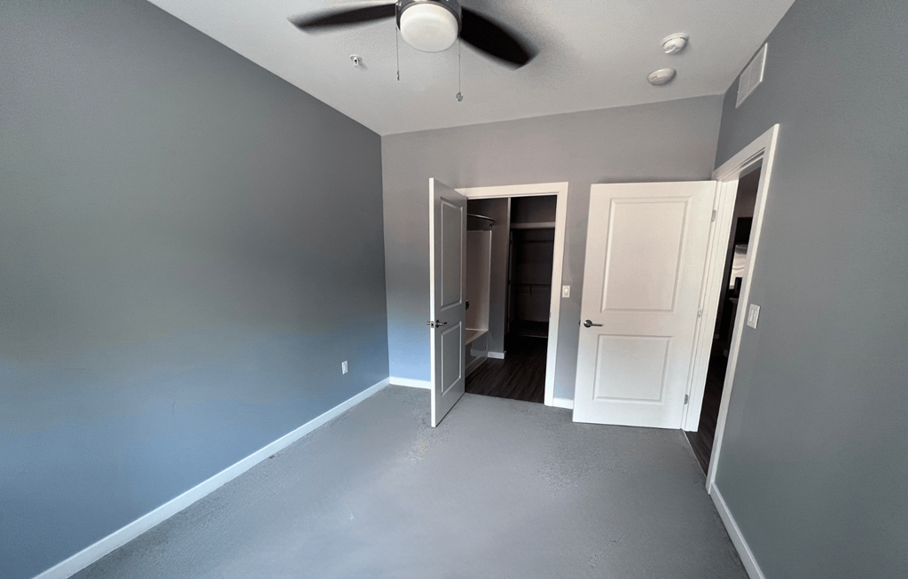 A room with a ceiling fan and two doors.