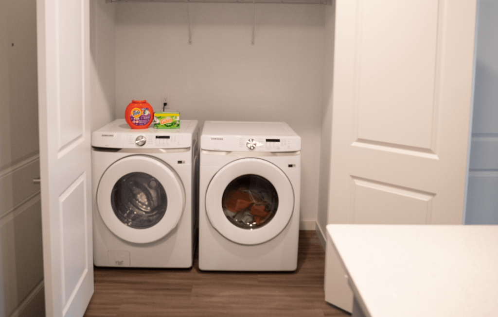 Two white front loading washing machines in a small laundry room.