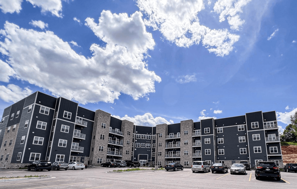an apartment building in a parking lot under a cloudy sky
