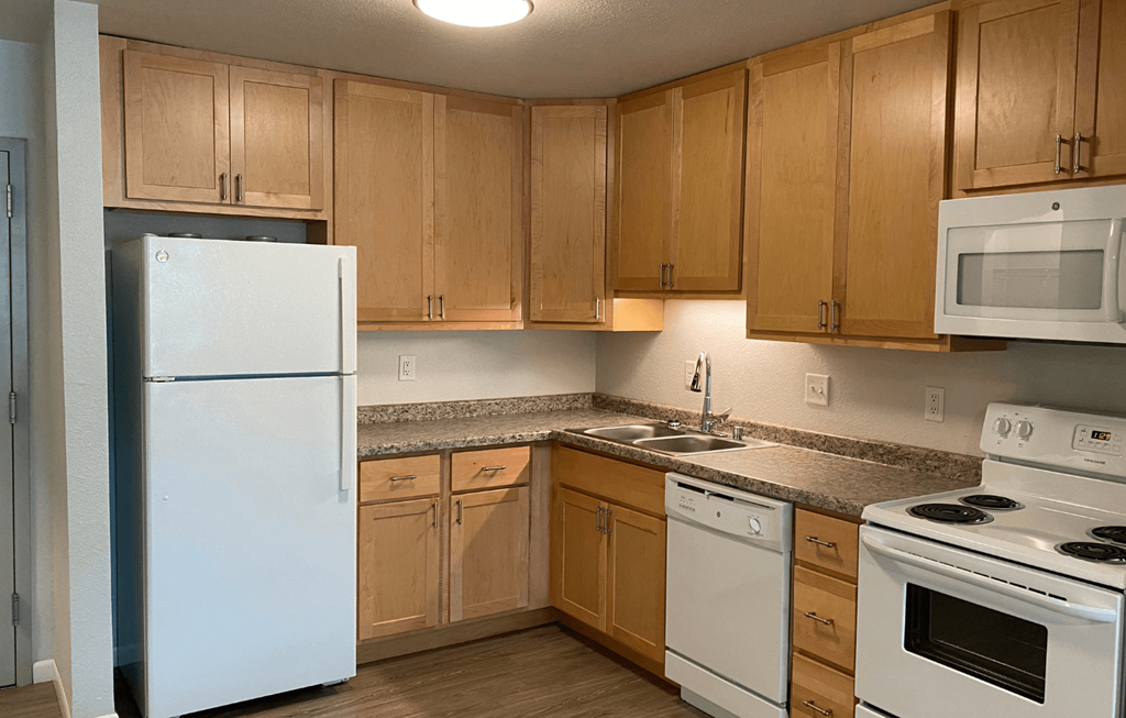A kitchen with white appliances and wooden cabinets.
