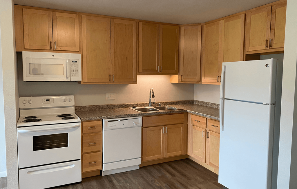A kitchen with white appliances and wooden cabinets.
