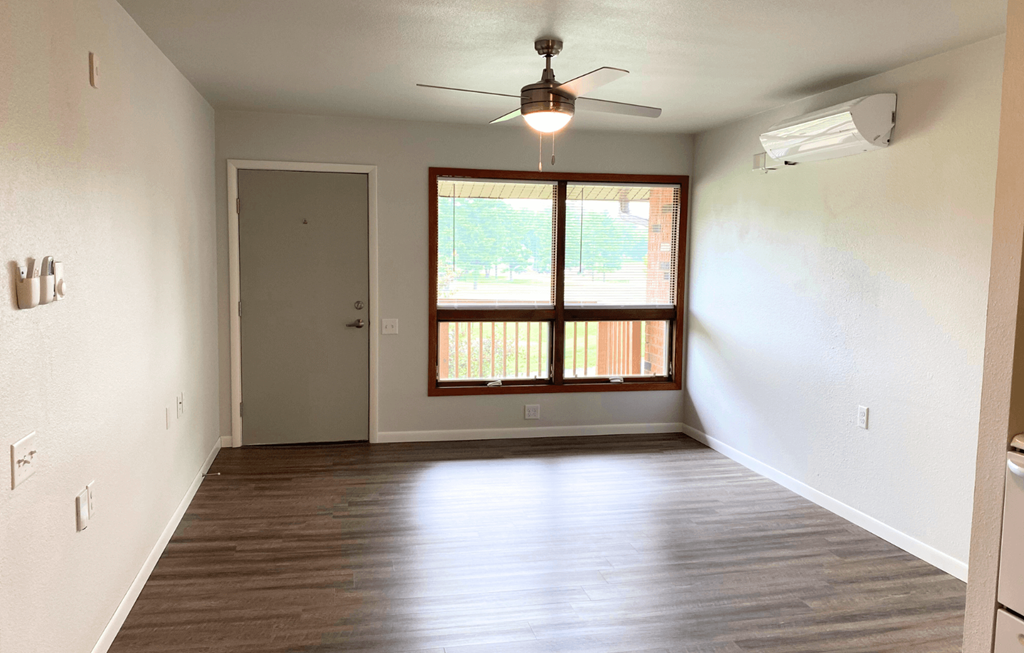 A room with a ceiling fan and a window with blinds.