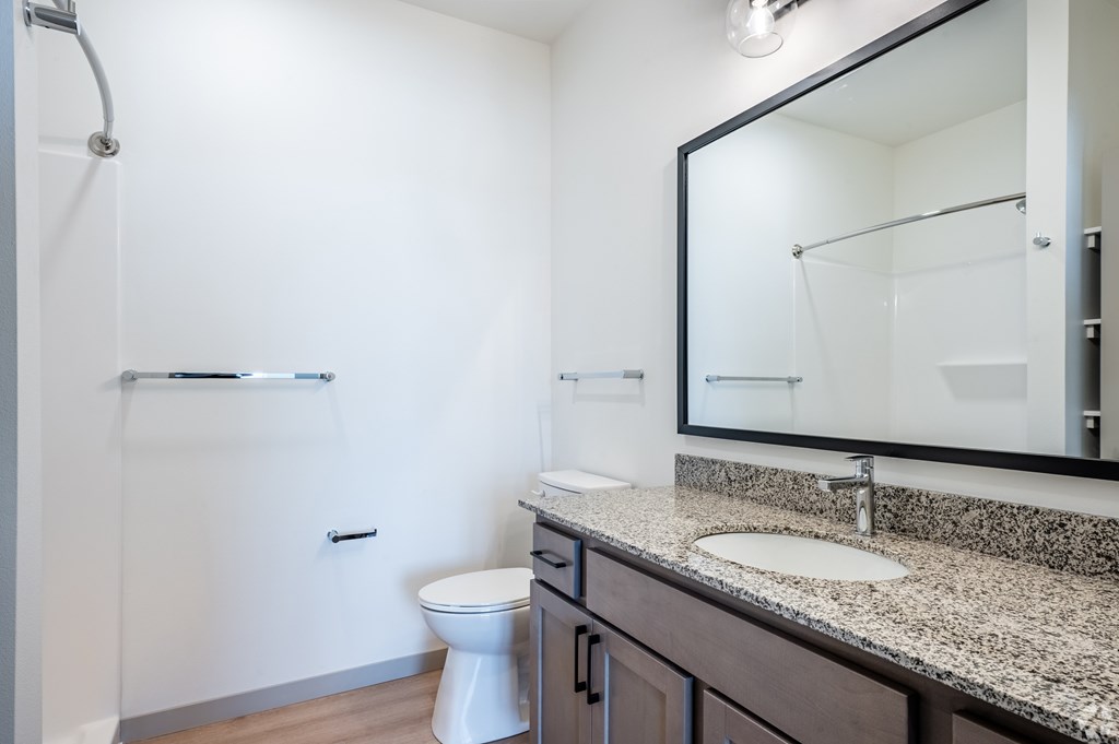 A white toilet sits in a bathroom next to a sink.