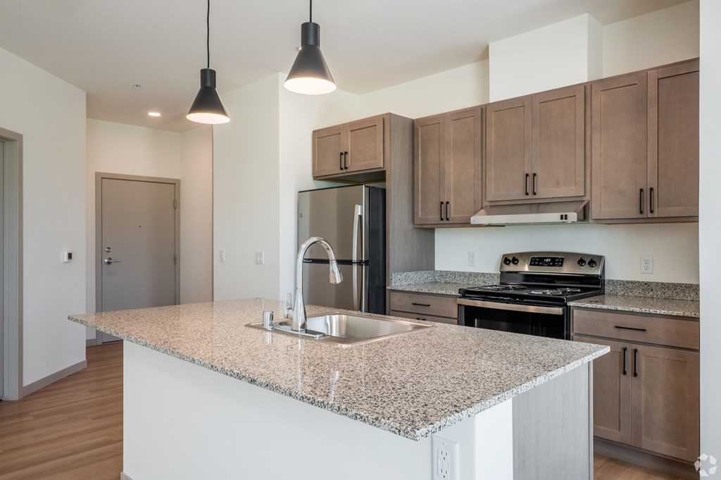 A kitchen with a granite countertop and stainless steel appliances.