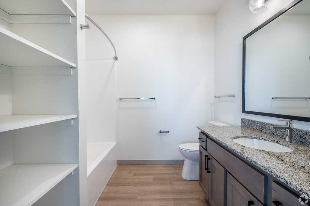 A bathroom with a toilet, sink, and mirror.