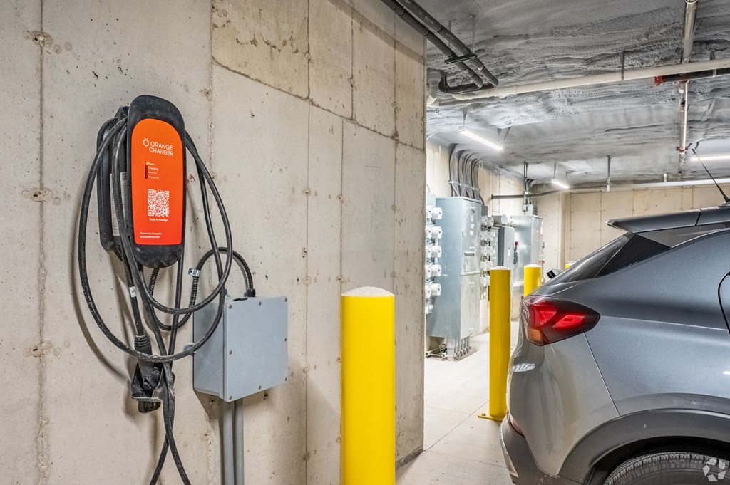 A grey car is parked next to a charging station.