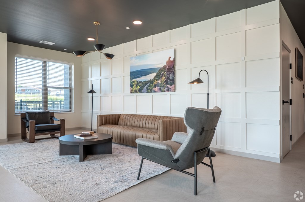 A modern living room with a grey chair and a white wall.