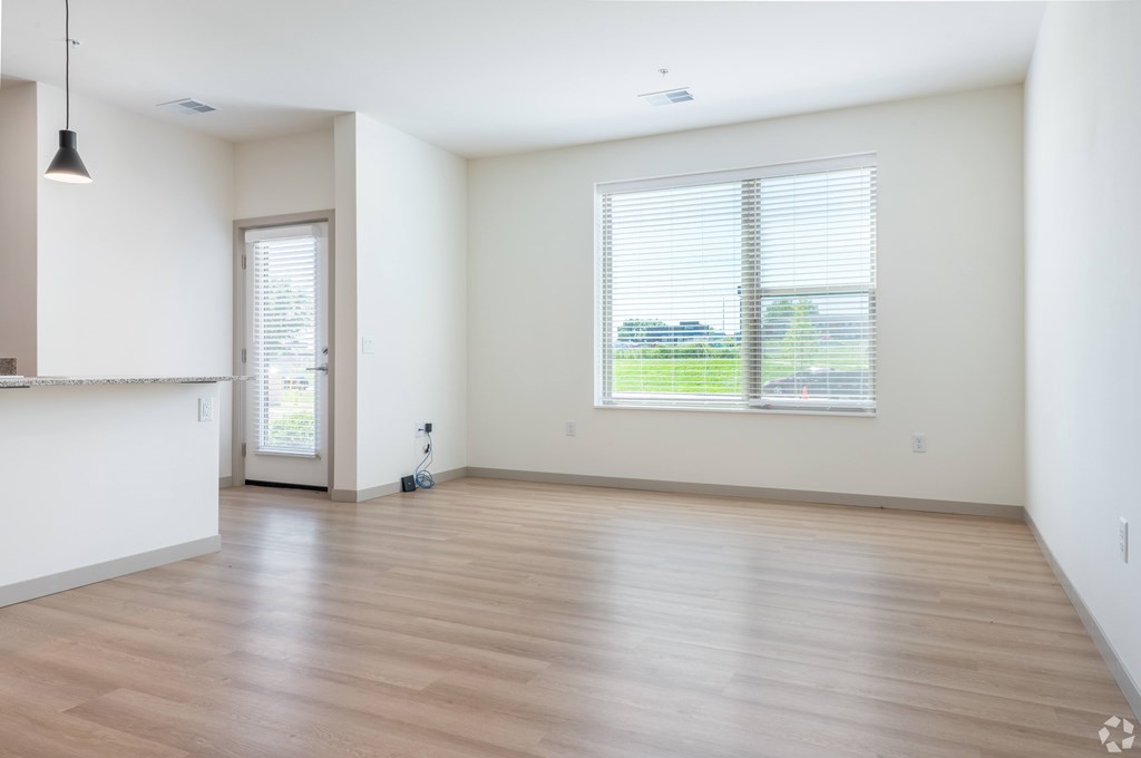 A room with wooden flooring and a window with blinds.