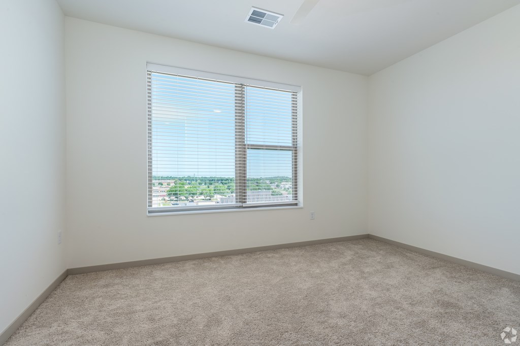 A room with a carpeted floor and a window with blinds.