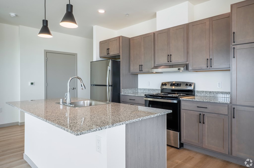 A kitchen with a granite countertop and stainless steel appliances.