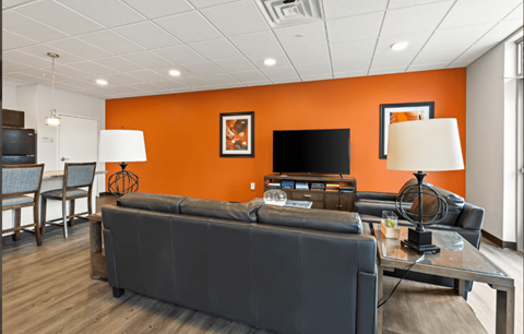 A living room with a grey couch, a glass coffee table, and a television.