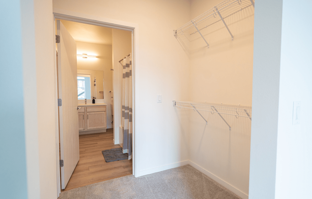 a walk in closet with clothes rails and a bathroom with a sink and a mirror