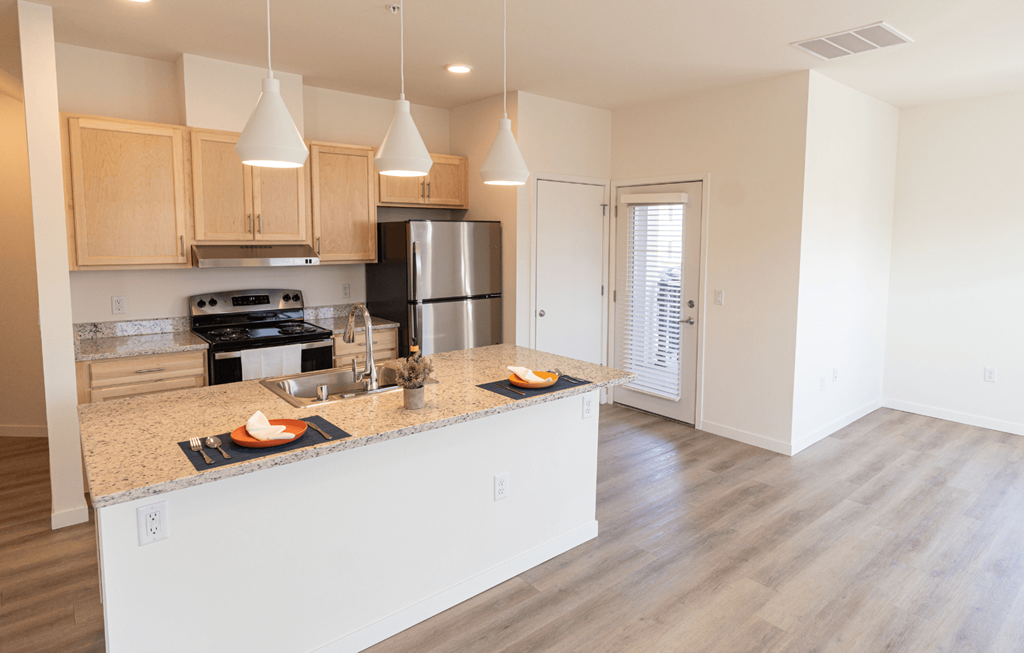 a kitchen with a large island and a stainless steel refrigerator