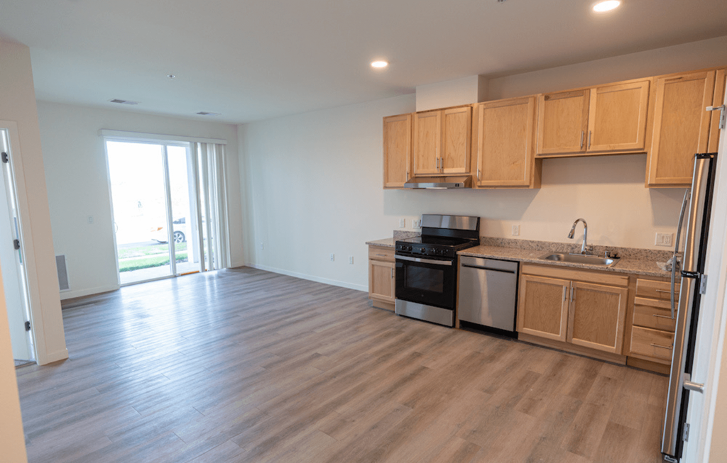 a kitchen and living room with wood flooring and wooden cabinets