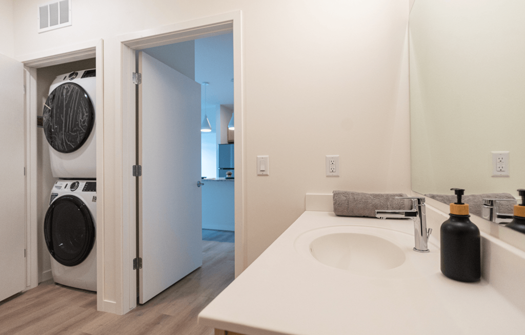 a white bathroom with a washer and dryer in it and a white sink