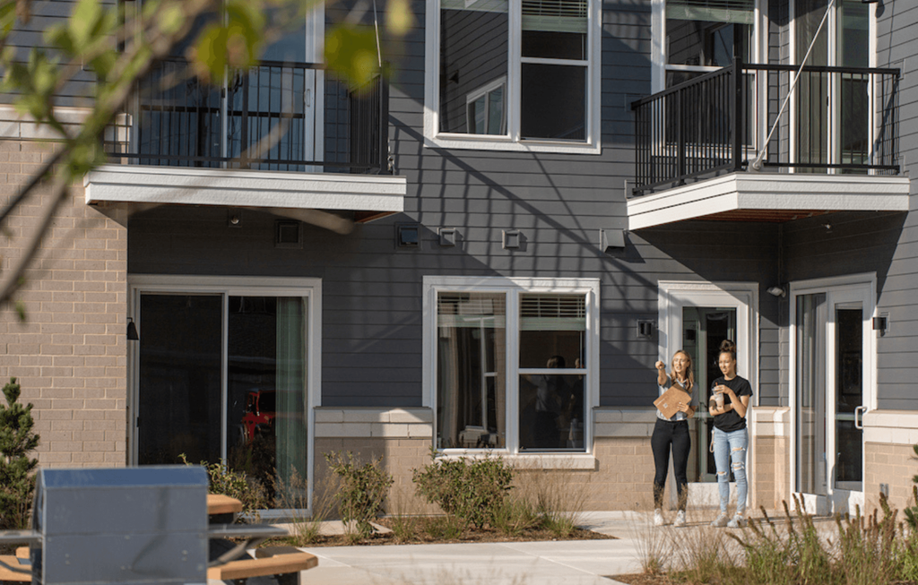 three people standing in front of a house