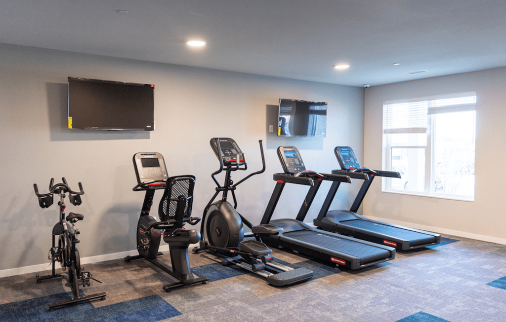 a gym with cardio equipment and a tv on the wall