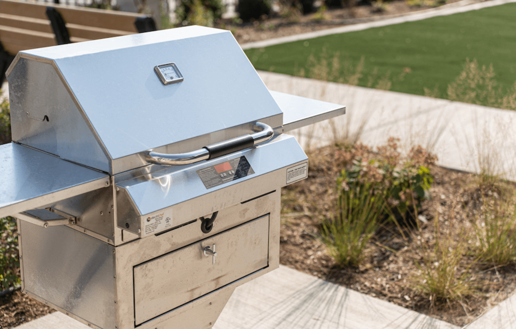 a silver smoker grill sitting on a table in a garden