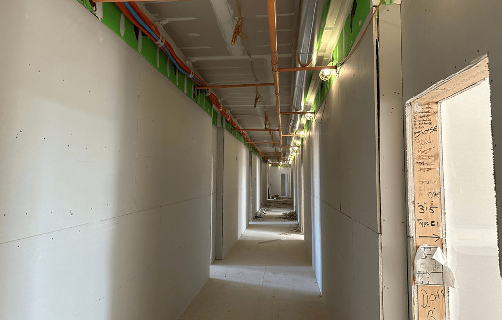 a hallway in a building under construction with pipes on the ceiling