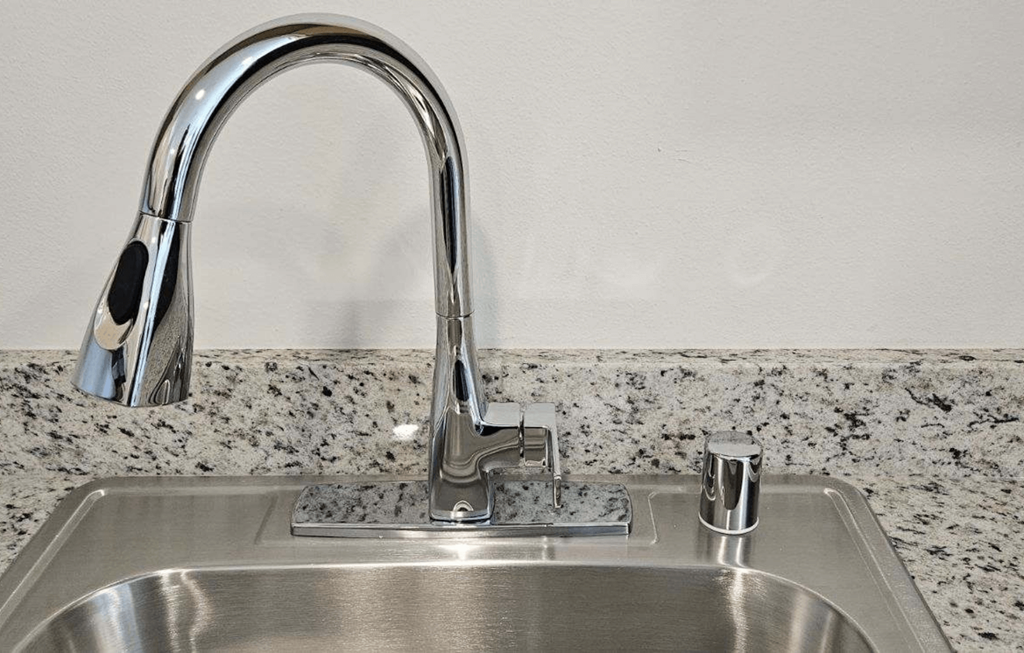 a kitchen sink with a faucet and a marble counter top