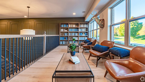 A living room with a long wooden table and leather chairs.
