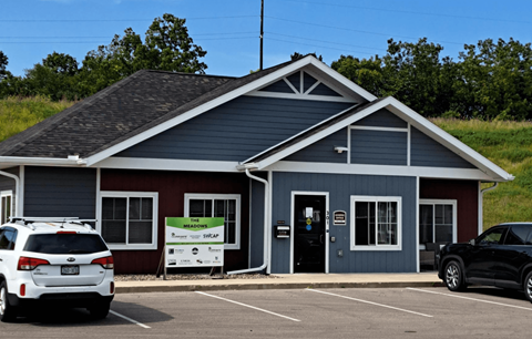 A small building with a red and blue exterior is surrounded by a parking lot.