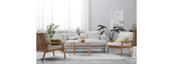 A living room with a white couch, a wooden chair, a wooden table, and a potted plant.