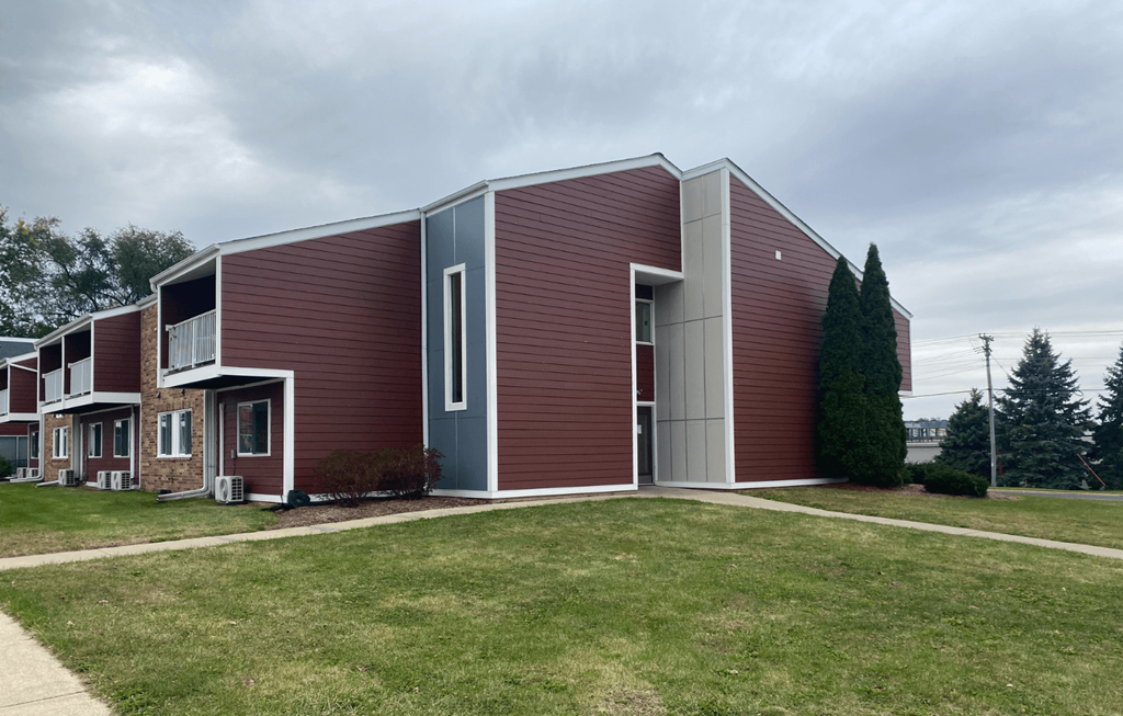 A modern house with a red brick exterior and a grey door.