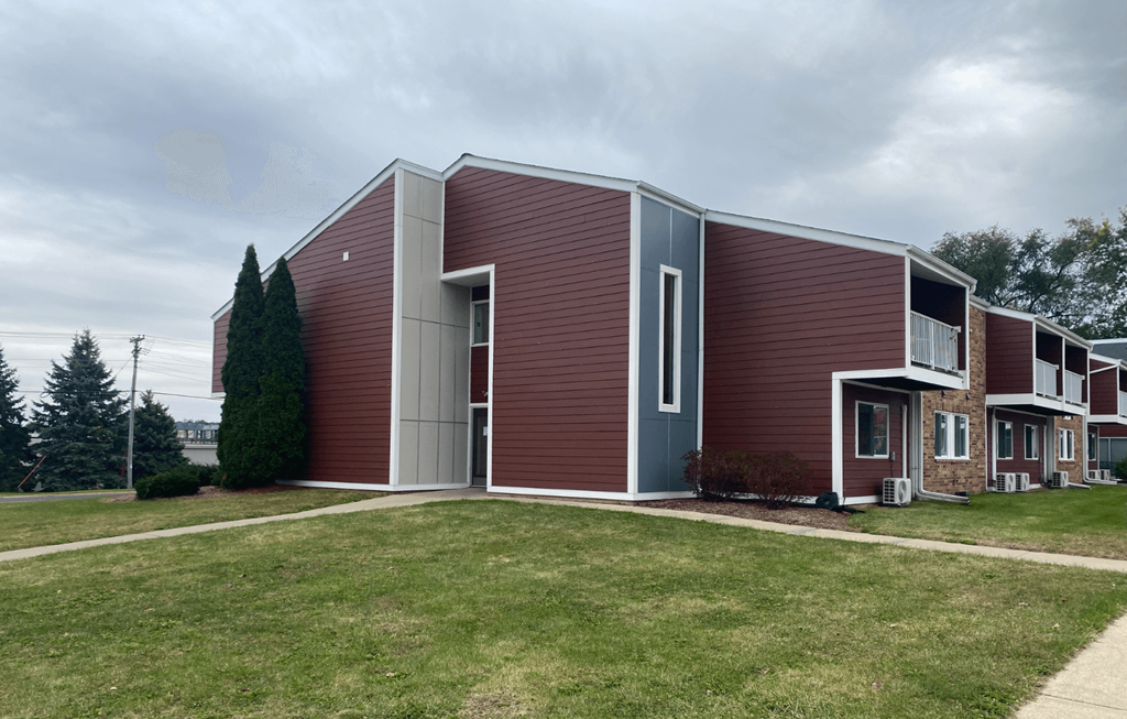 A modern building with a red brick exterior and a grey roof.
