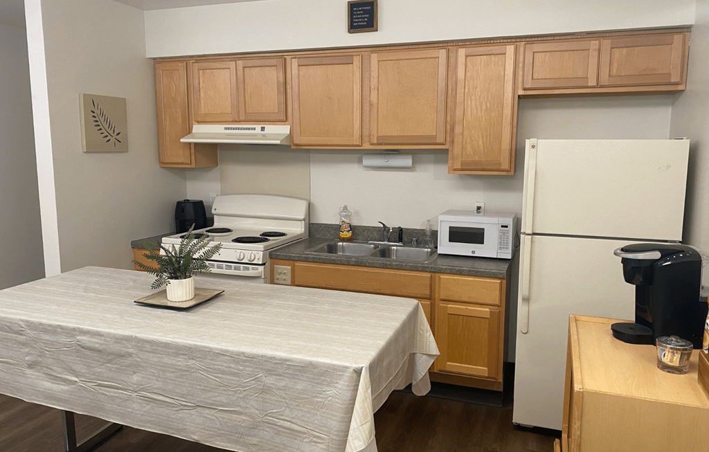 A kitchen with a table and a fridge.