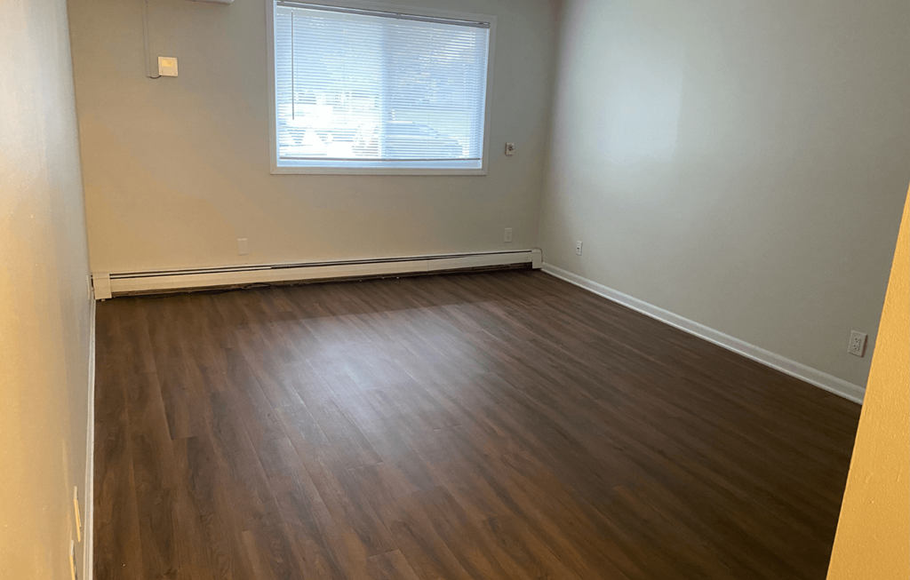 A room with wooden flooring and a window.