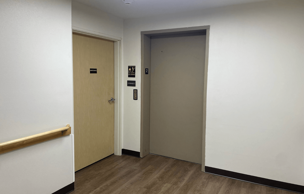 A hallway with two doors and a wooden handrail.