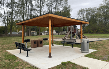 A wooden pavilion with a playground in the background.