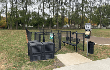 A park with a black fence, a bench, and a sign.