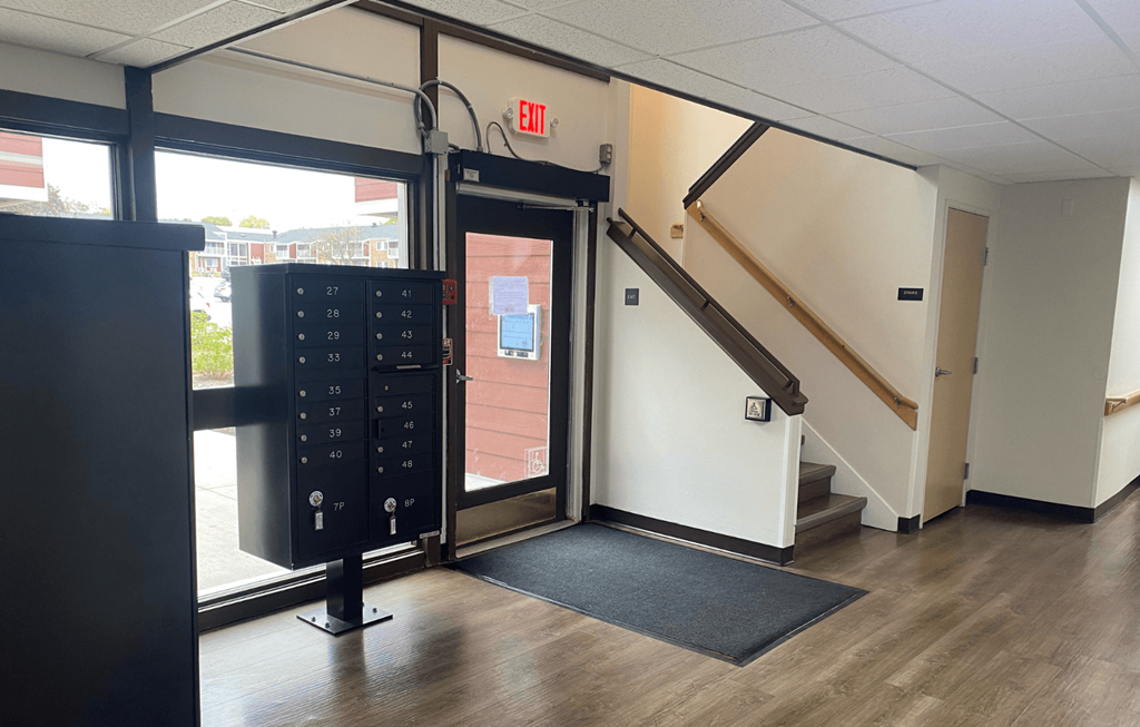 A black door with a keypad and a red exit sign above it.