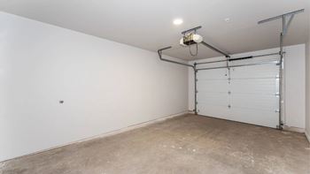 A white wall with a garage door opener and a light fixture.
