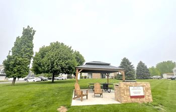 A gazebo with a sign that reads "Welcome to" is surrounded by trees and grass.