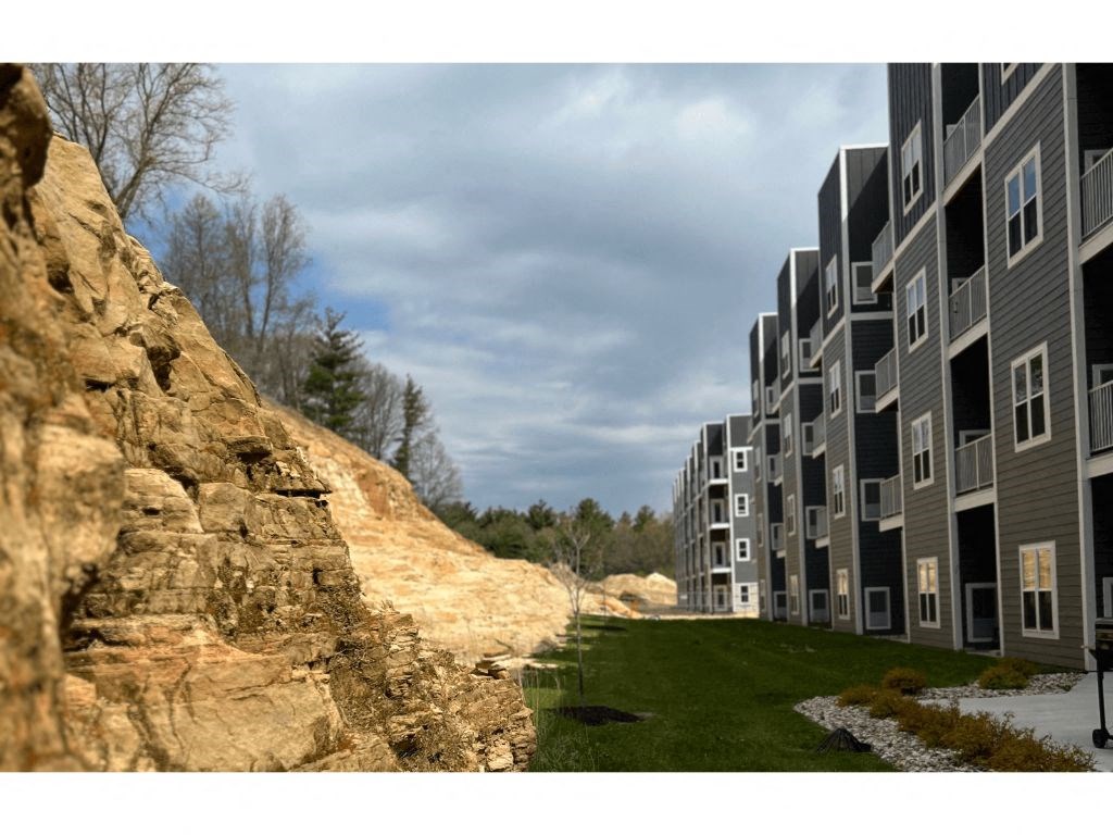 a view of an apartment complex with a large rock wall in the foreground