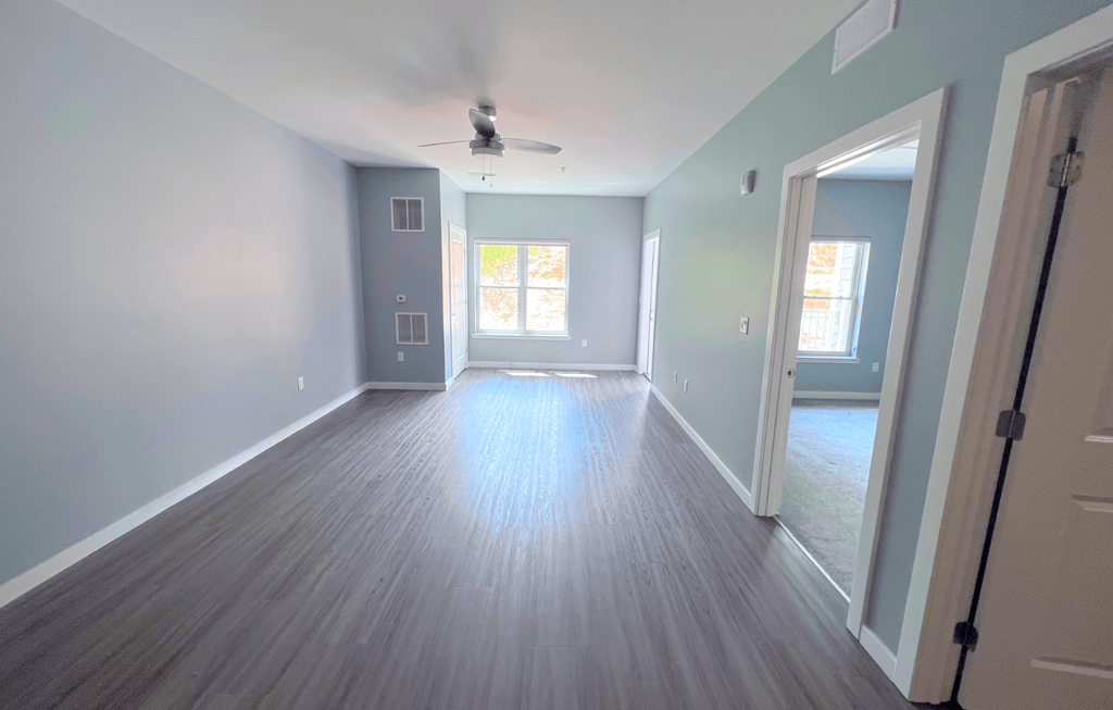 A room with a ceiling fan and wooden flooring.
