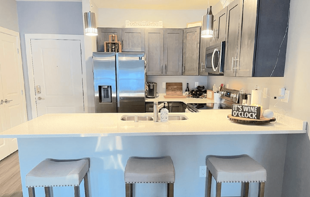 A kitchen with a white countertop and bar stools.