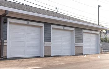 Three garage doors are closed and the building is grey.