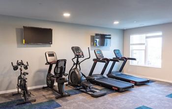 A room with a television, a window, and exercise equipment.