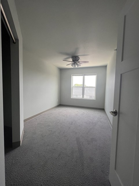 an empty room with a ceiling fan and a window