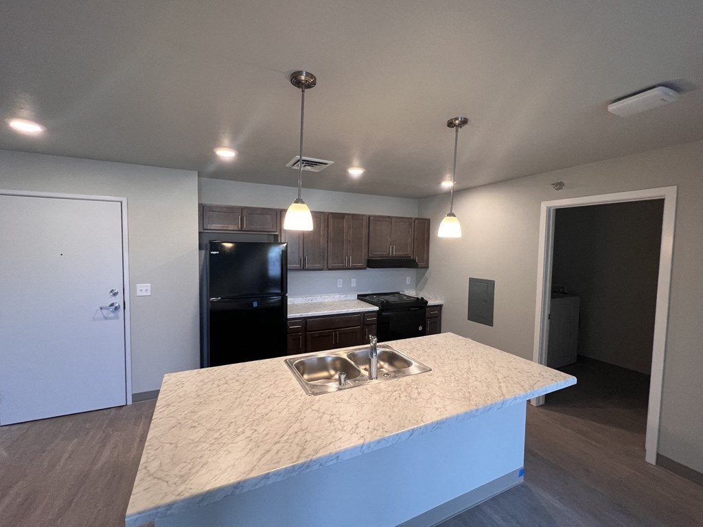 a kitchen with a large island and a black refrigerator