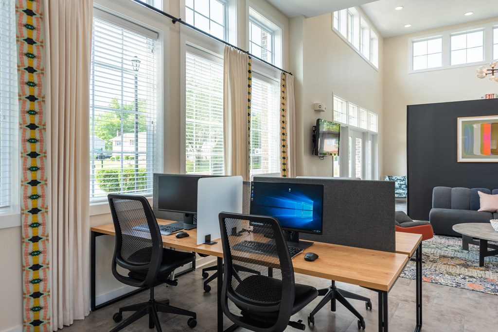 a room with two computers and chairs in front of windows