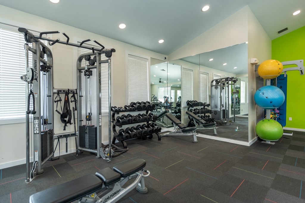 a gym with weights and cardio equipment on the floor and mirrored walls