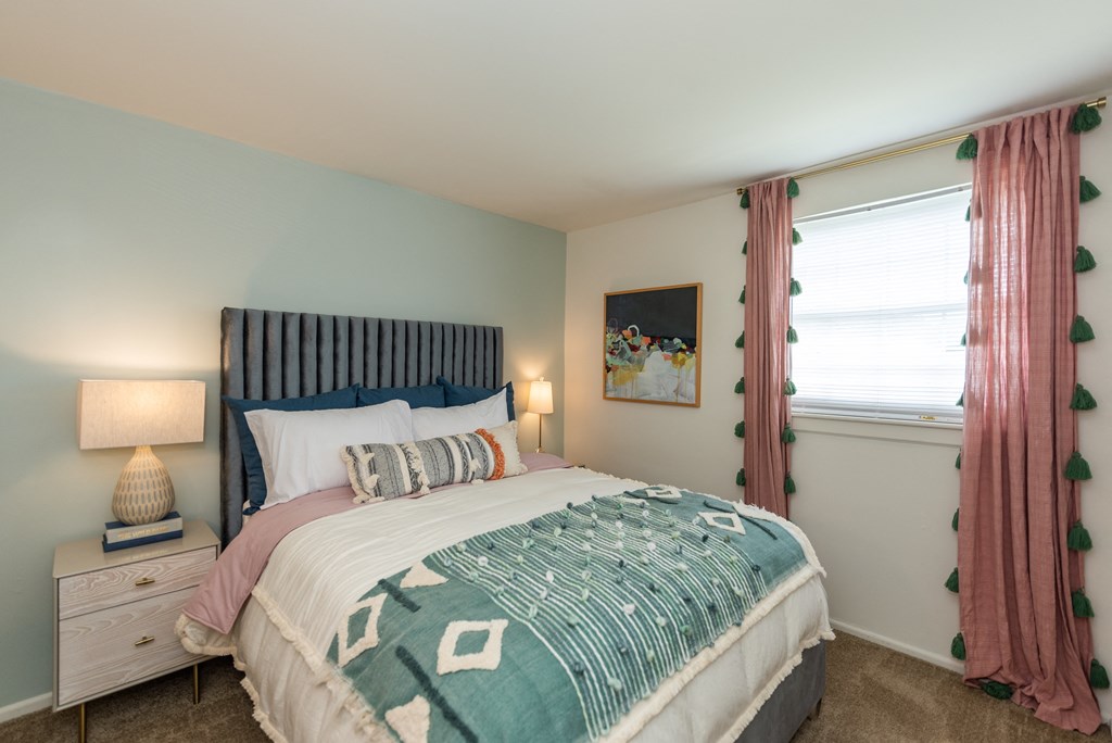 a bedroom with a bed and a window with pink curtains