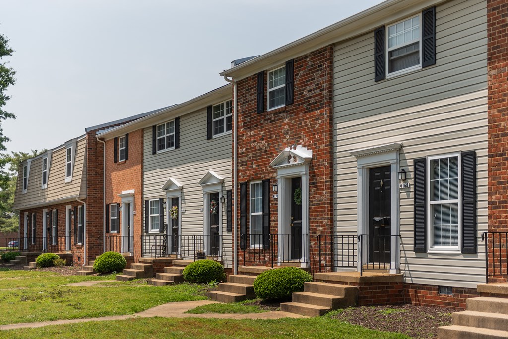 a row of town houses with steps and a lawn