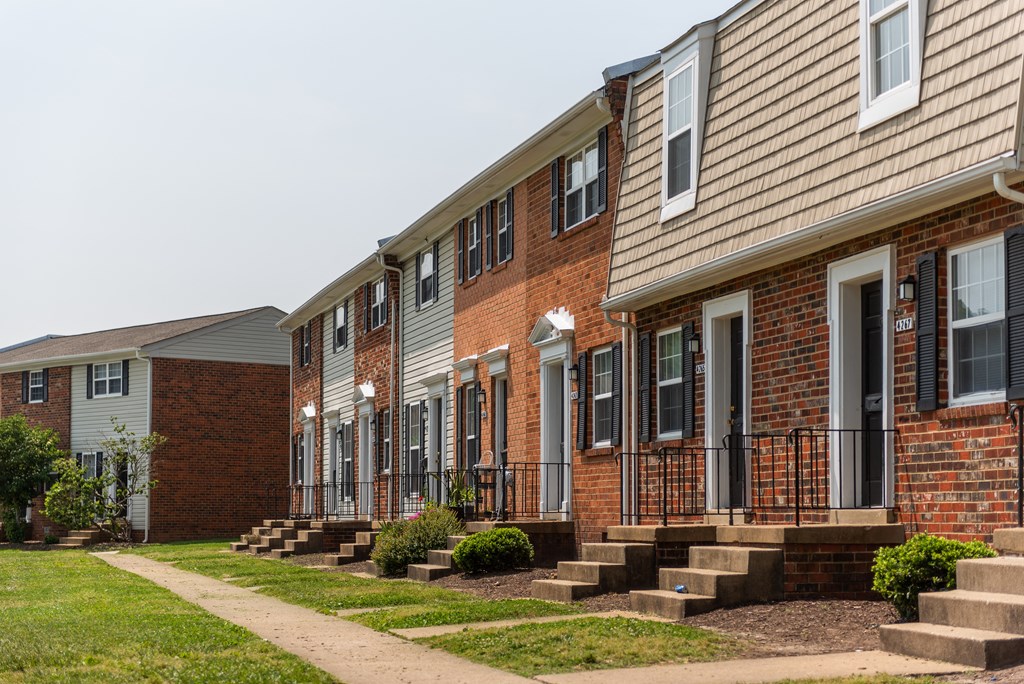 a row of brick apartments with steps and grass in front of them
