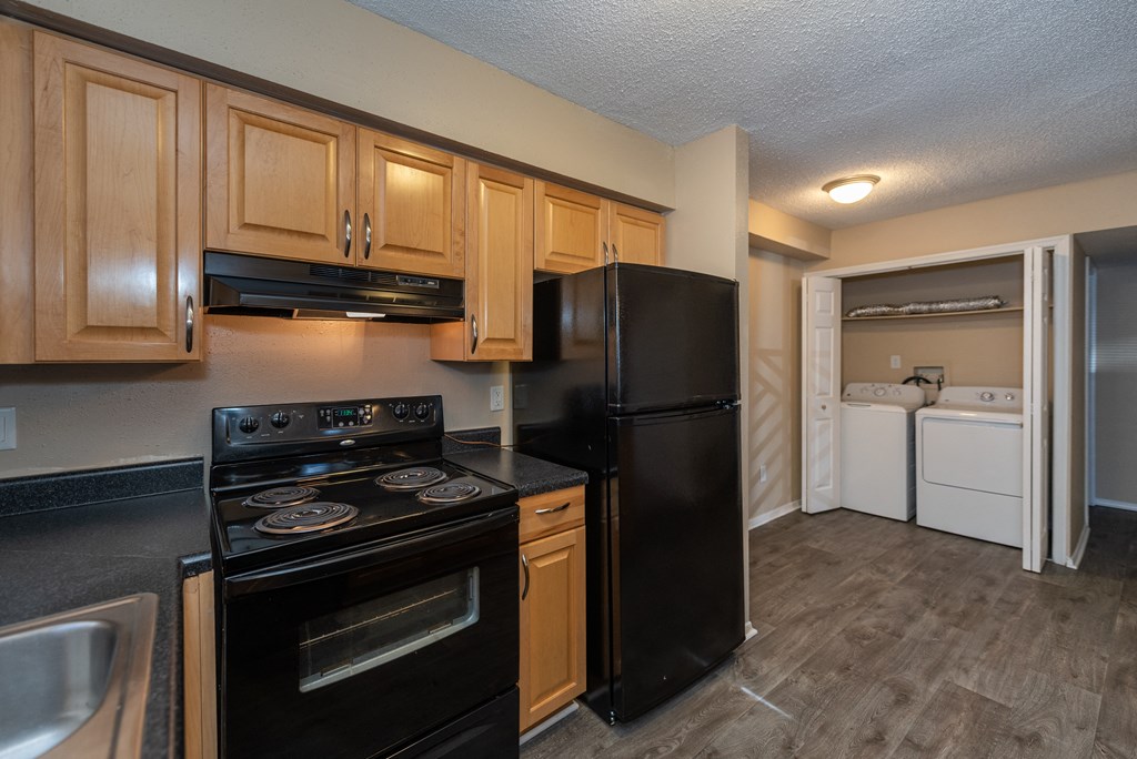 A kitchen with black appliances and wooden cabinets.